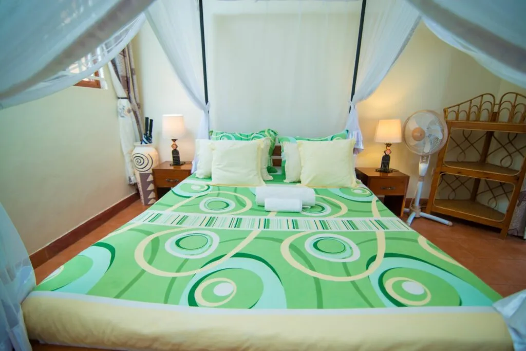 A comfortable en-suite double room with mosquito-net draped bed