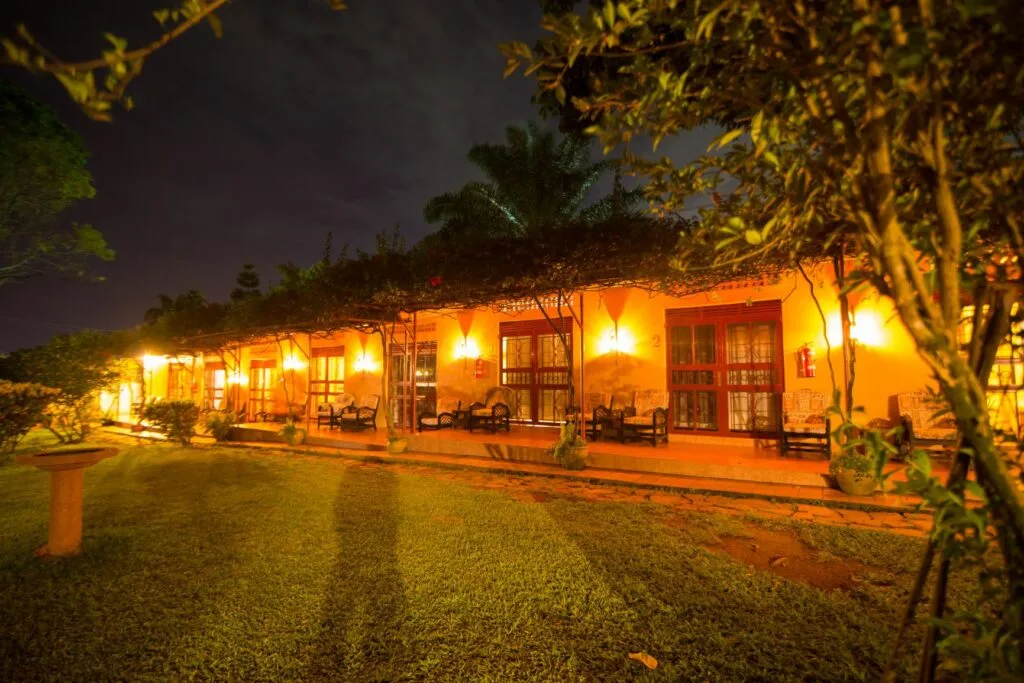 The guesthouse's veranda rooms glow warmly in the evening garden