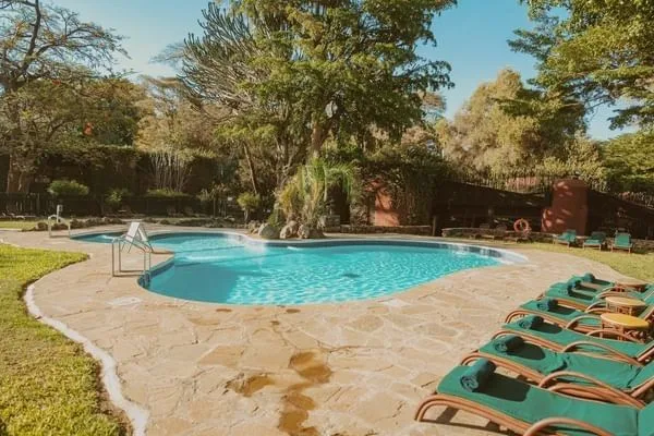 Guests relax poolside surrounded by lush tropical gardens within the lodge grounds.