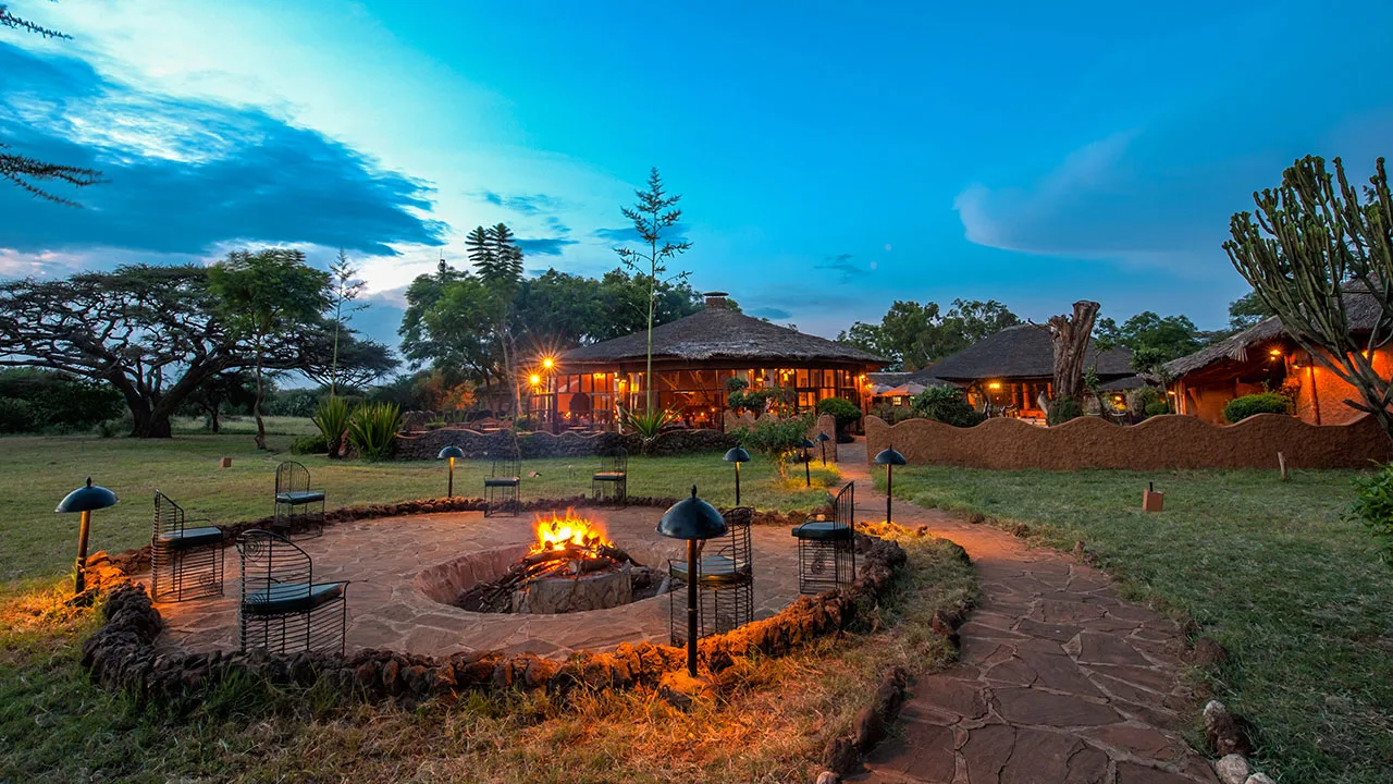 The lodge's fire pit gathering area at dusk, framed by traditional thatched roofs