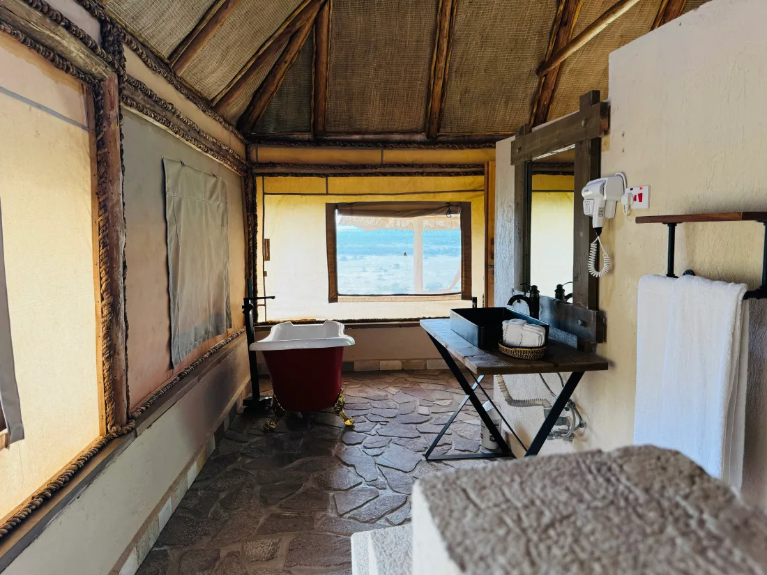 A freestanding bathtub framed by sweeping savanna views