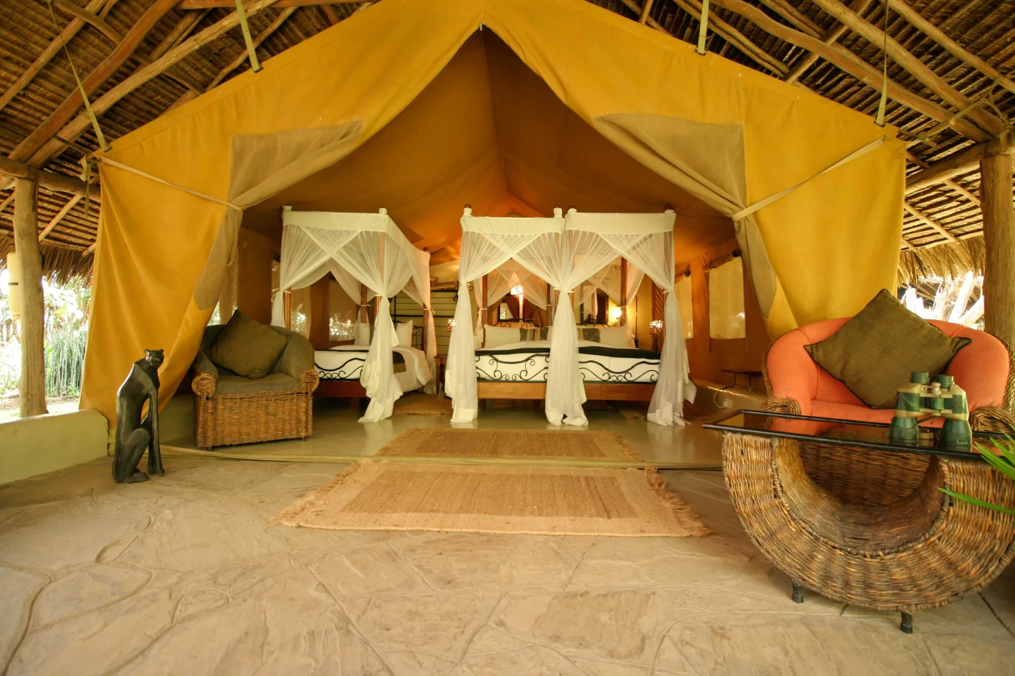 A twin tent interior with four-poster beds and mosquito netting