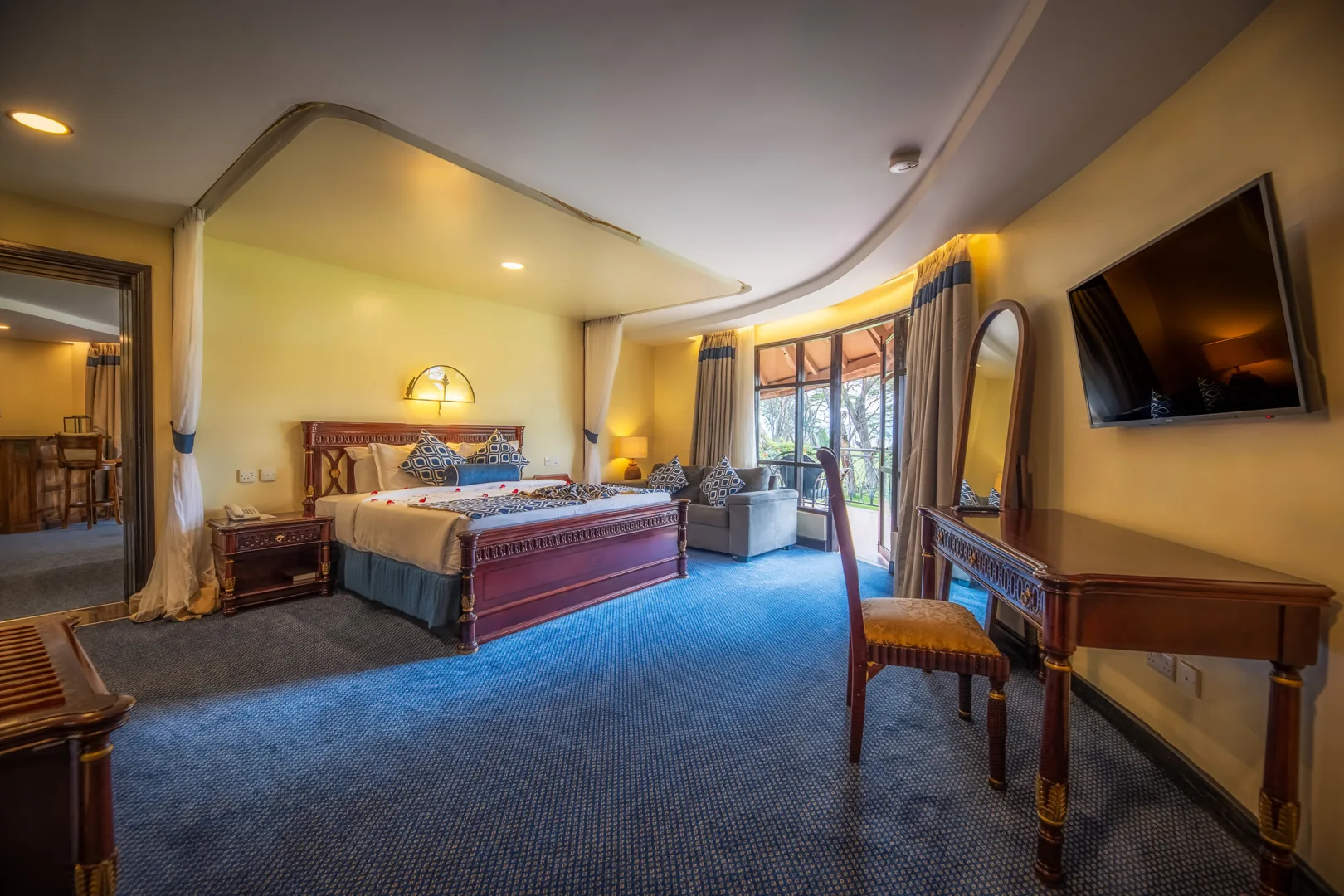 A spacious guest room with warm decor and a private balcony overlooking the grounds