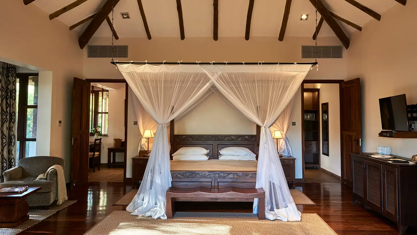 Spacious cottage bedroom with vaulted timber ceilings and a canopy bed