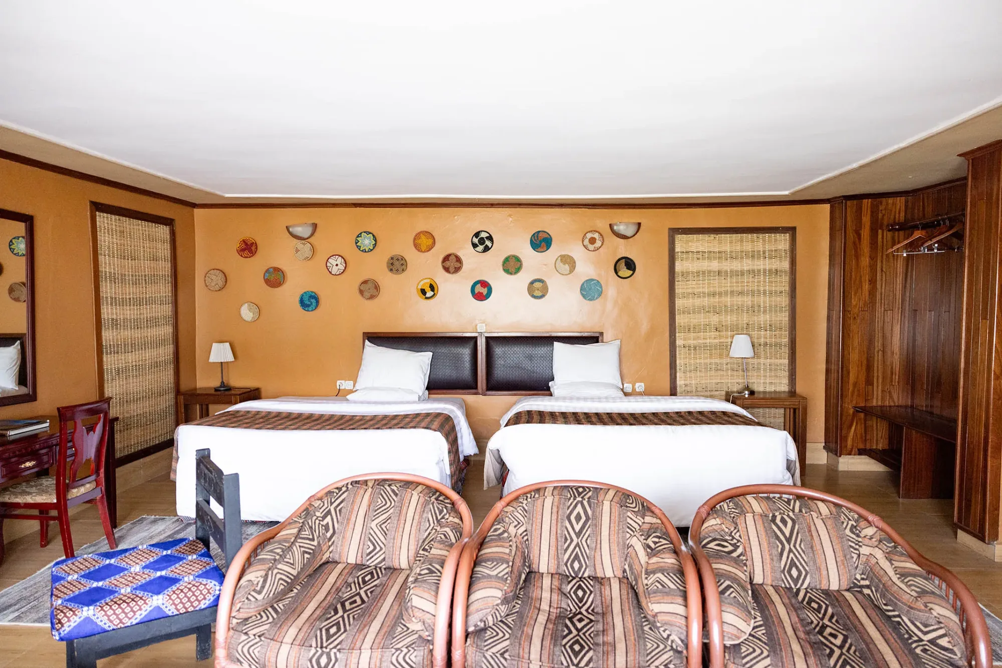 A twin room with writing desk, wardrobe, and the lodge's signature basket-adorned walls.