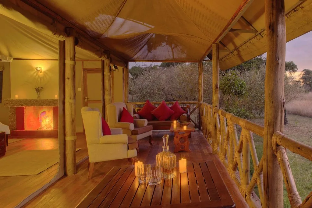 A furnished deck with fireplace glow offers a quiet lounge space just outside each tent.
