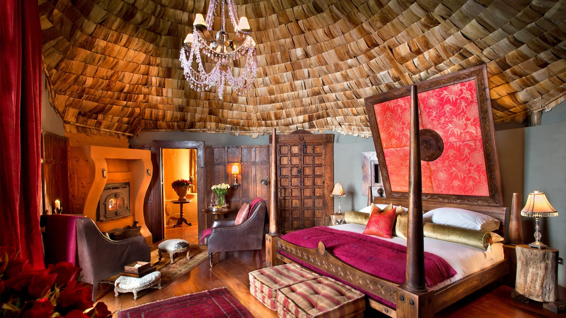 Each suite blends carved wooden furniture, plush fabrics, and a grand chandelier with sweeping crater views.