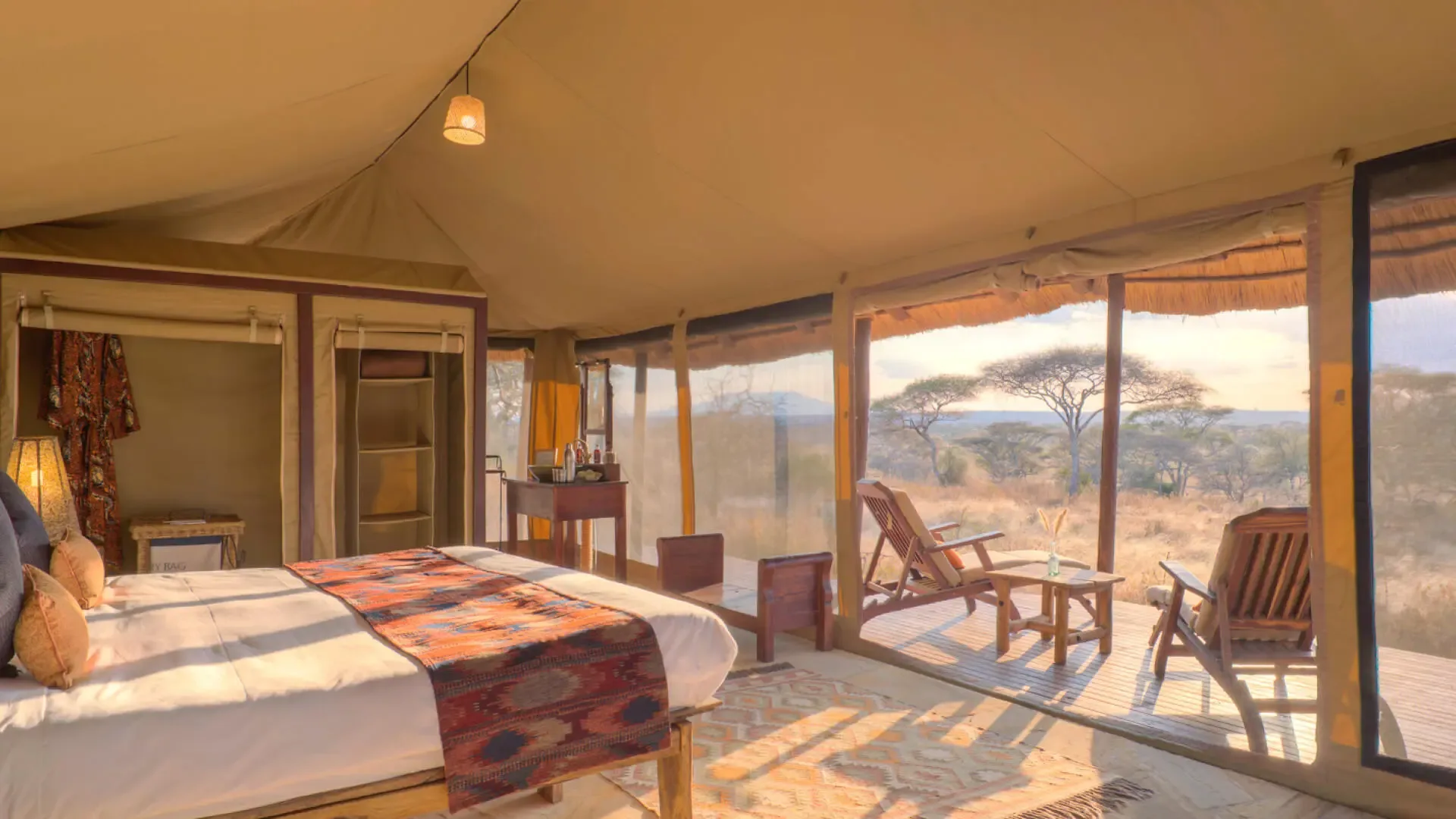 Inside a guest tent: a mosquito-net draped bed and hand-carved mahogany furniture.