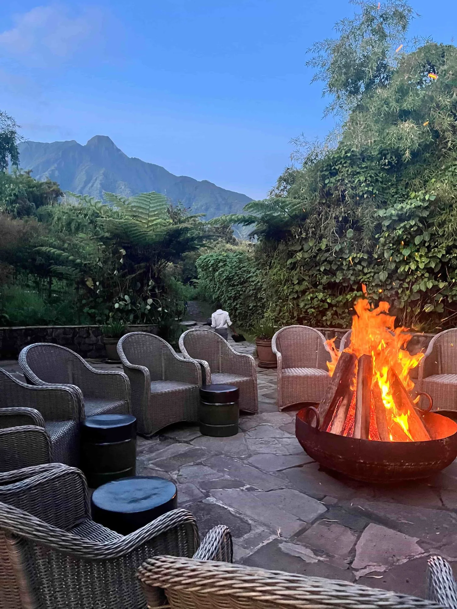 Guests gather around the outdoor firepit lounge with views toward the Virunga peaks.