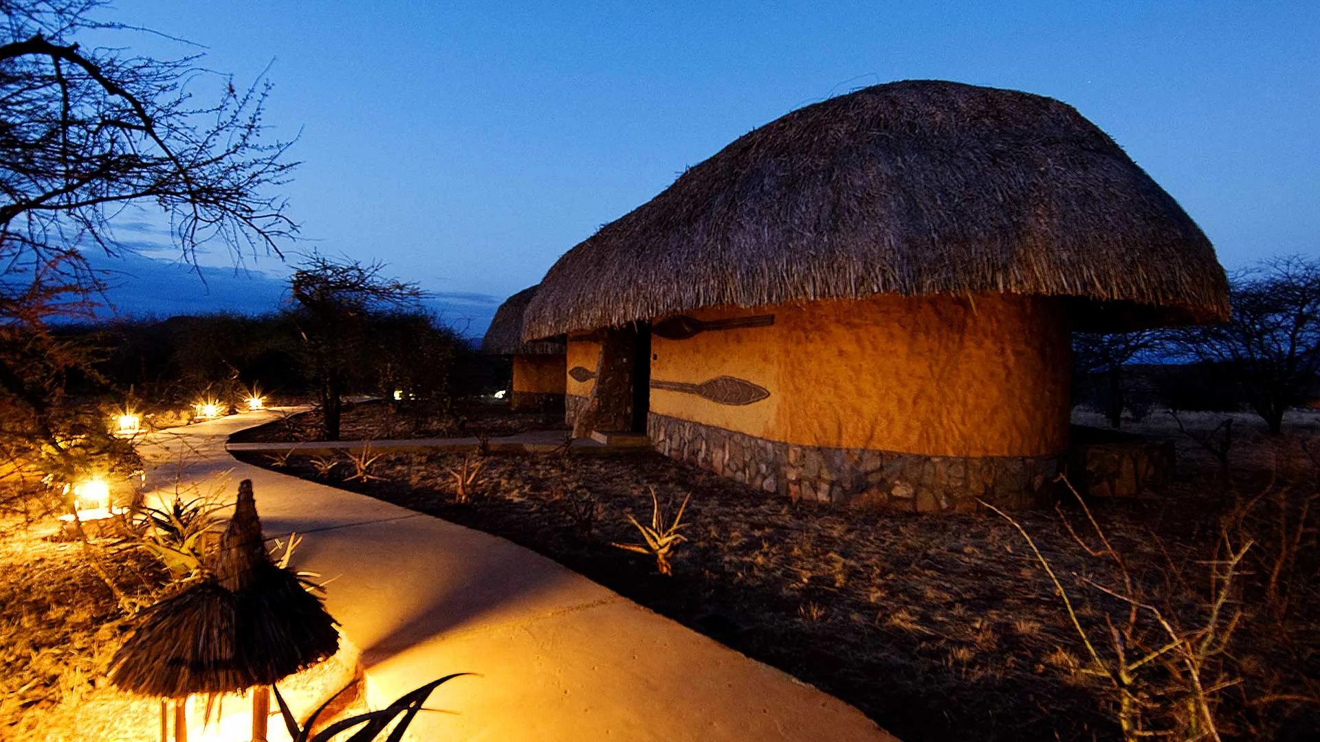 Lantern-lit pathways lead to the cottages as dusk settles over the reserve.