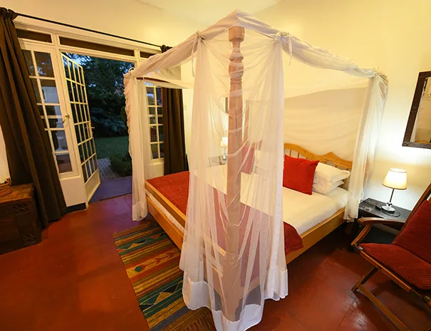 A garden-view suite with a mosquito-net draped four-poster bed