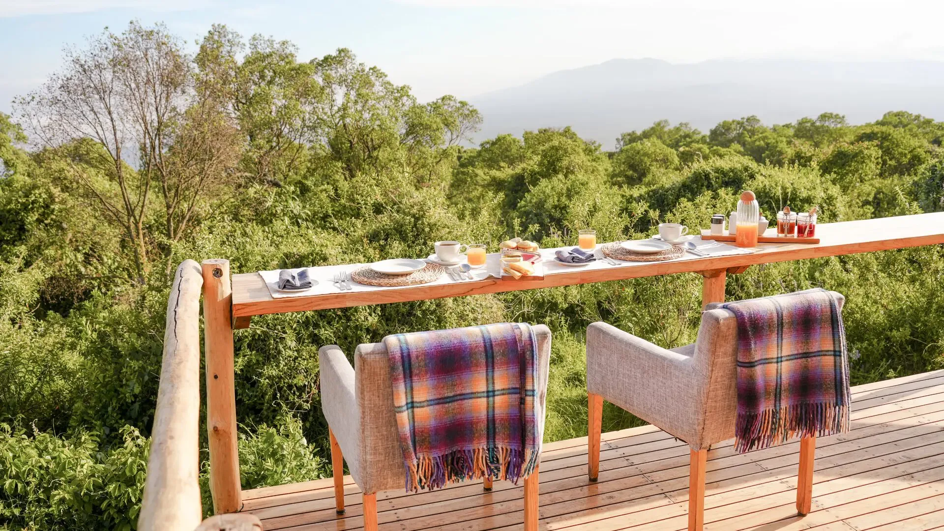 Breakfast on the deck looks out over dense montane forest toward distant volcanic peaks.