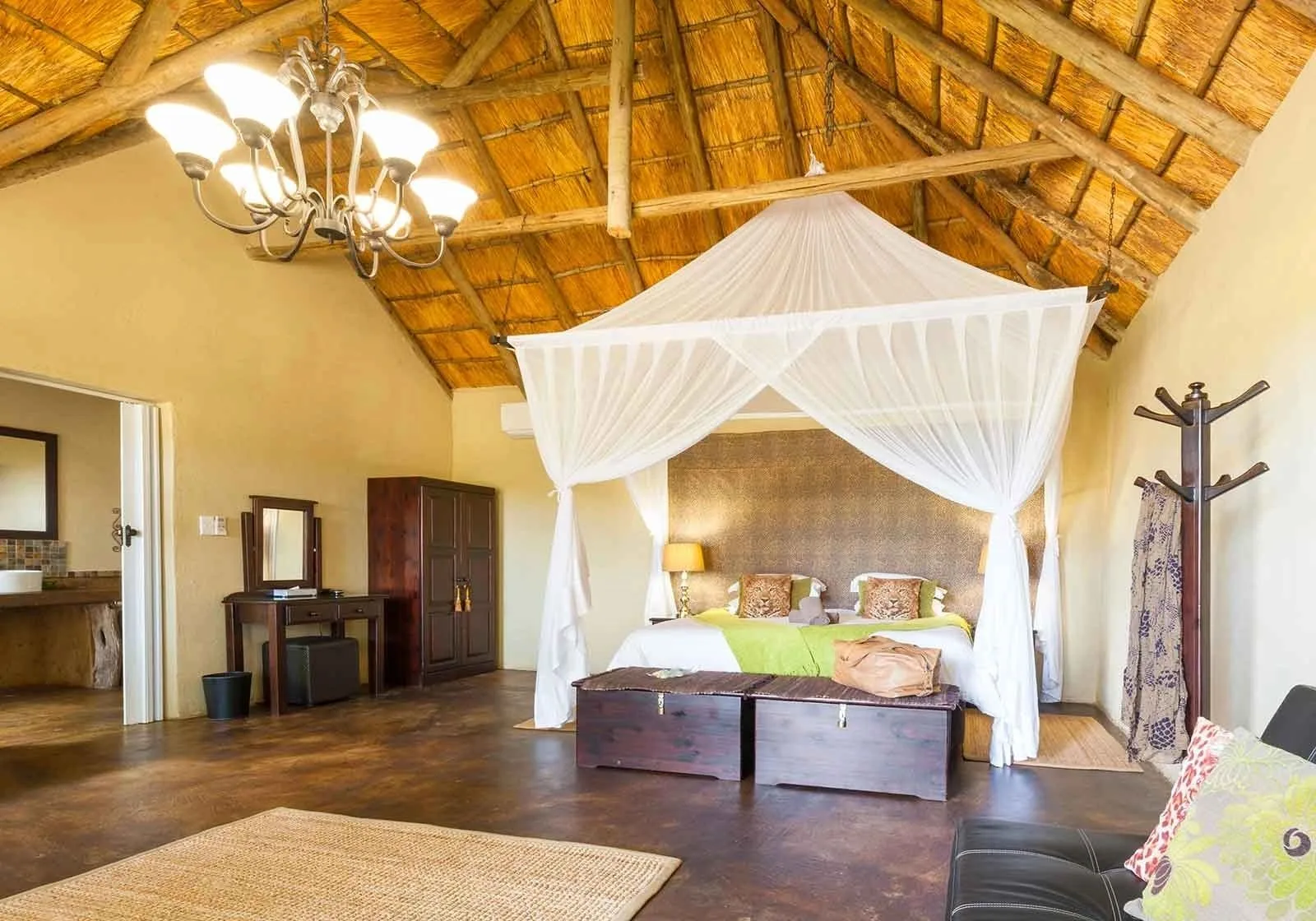 A Superior Chalet with vaulted thatch ceiling and canopied bed.