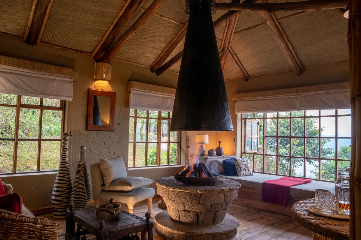 Inside a deluxe banda, a central hanging fireplace warms the sitting area beside a window seat.