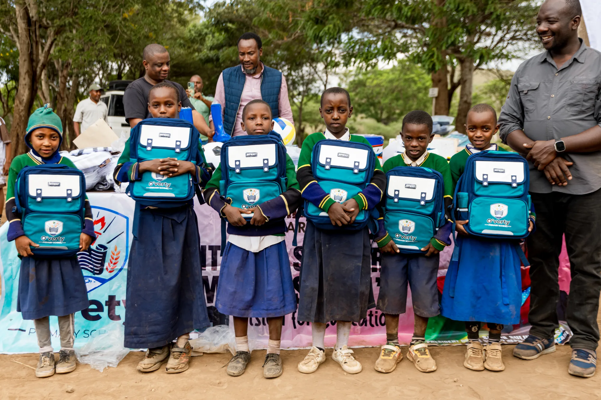 Volunteers and schoolchildren in high-visibility gloves standing behind the waste they collected on a coastal cleanup