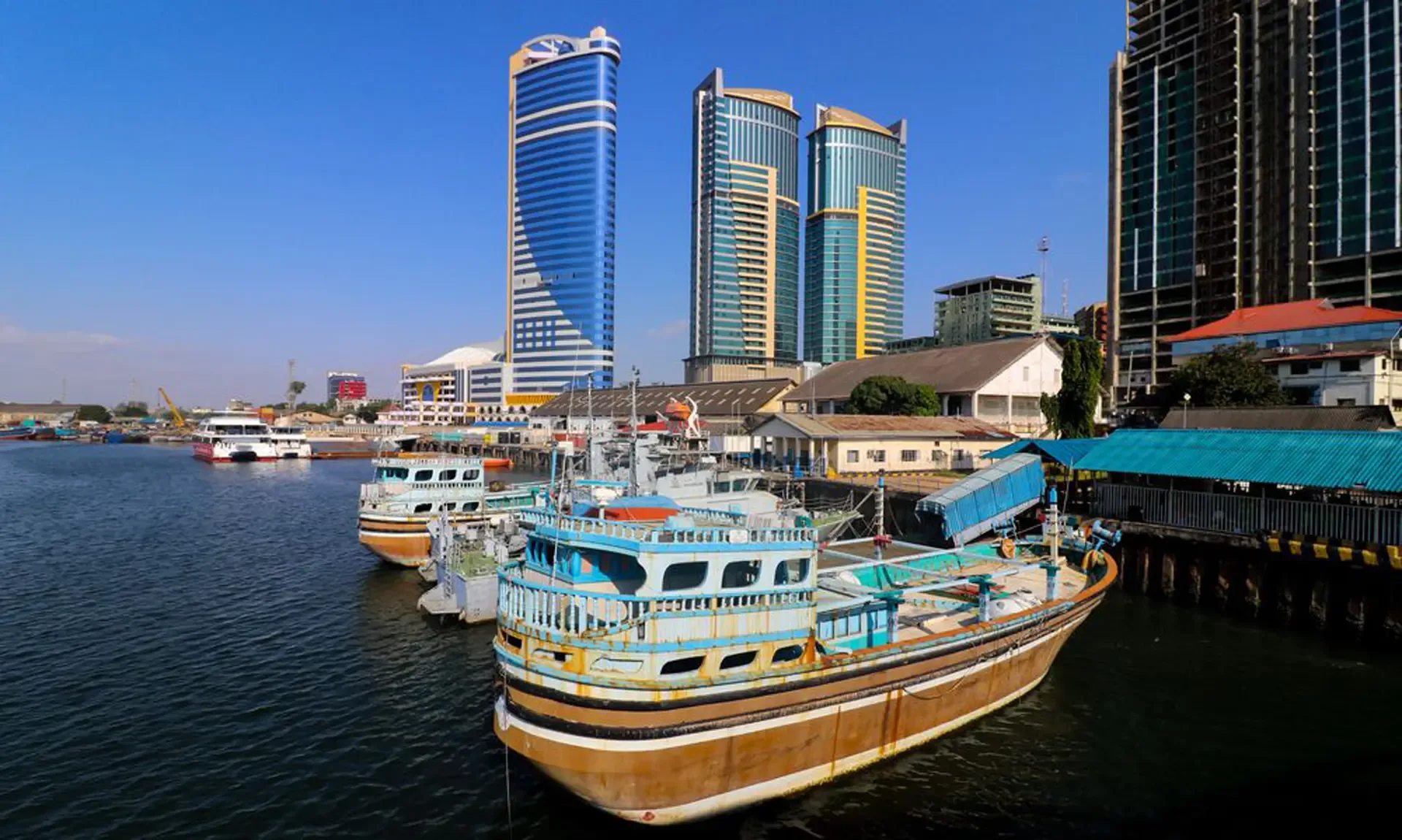 Wooden boats with blue and white cabins moored in a harbour on a clear day.