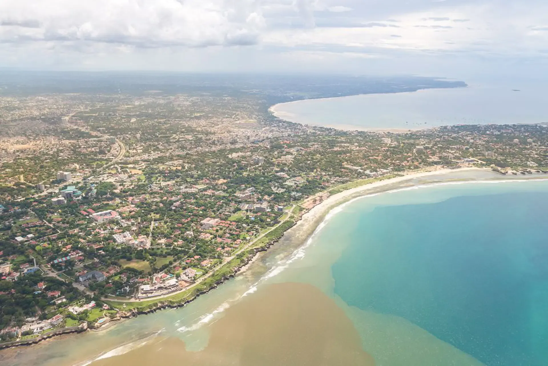 Aerial view over Zanzibar's coast, where green streets meet the curving shore.