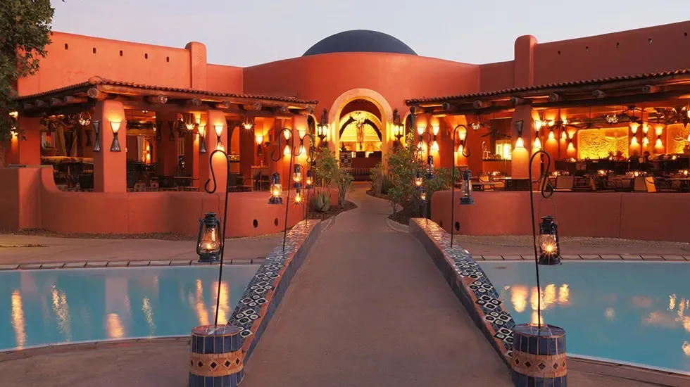 Lantern-lit walkway between the pools at Avani Victoria Falls Resort in Zambia at dusk.
