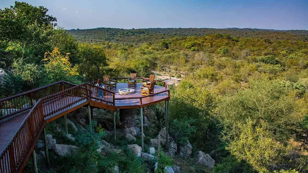 A timber deck and fire pit looking out over the bushveld of Balule Nature Reserve, South Africa.