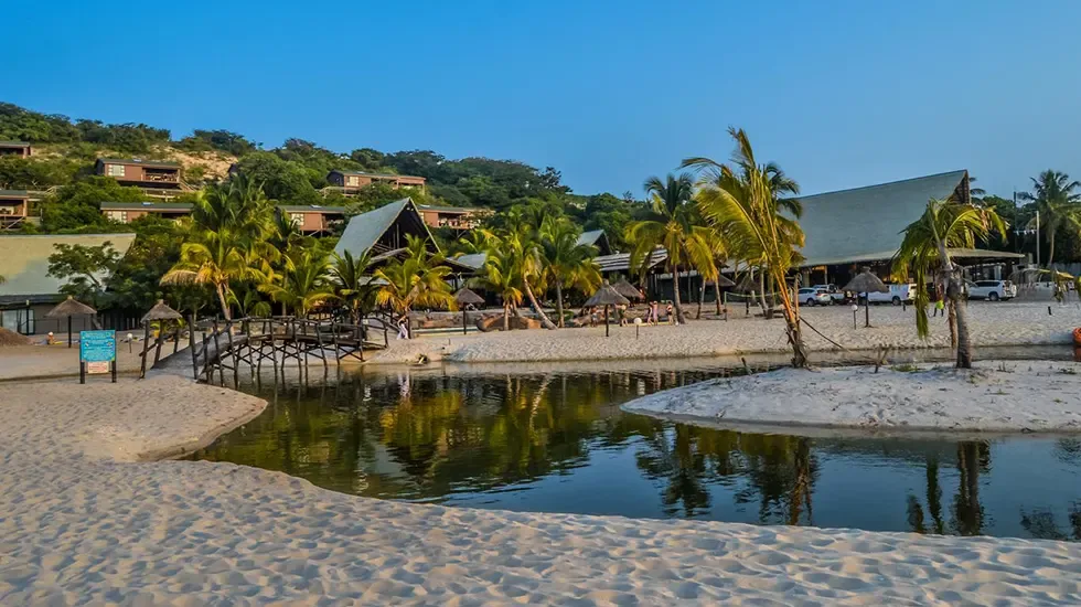 Palm trees and calm lagoon waters at a beachside resort in Bilene, Mozambique.