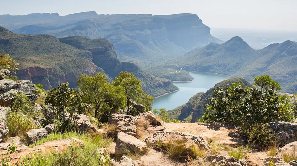 Green cliffs and still water seen from a rocky viewpoint in Blyde River Canyon Nature Reserve, South Africa.