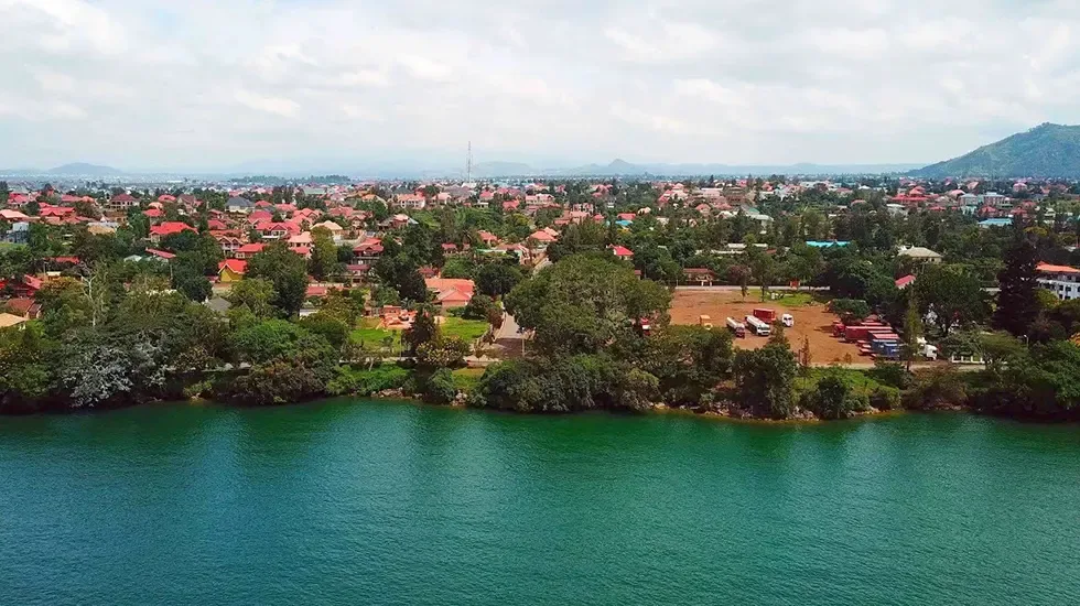 Red-roofed houses and tall trees line the shore of Lake Kivu at Gisenyi, Rwanda.