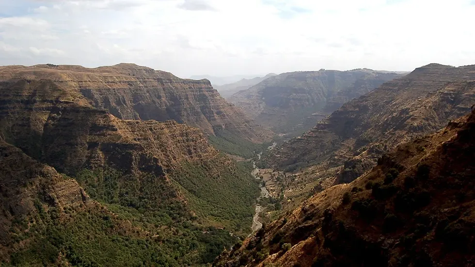 The Great Rift Valley opens into layered cliffs and a green valley floor below.
