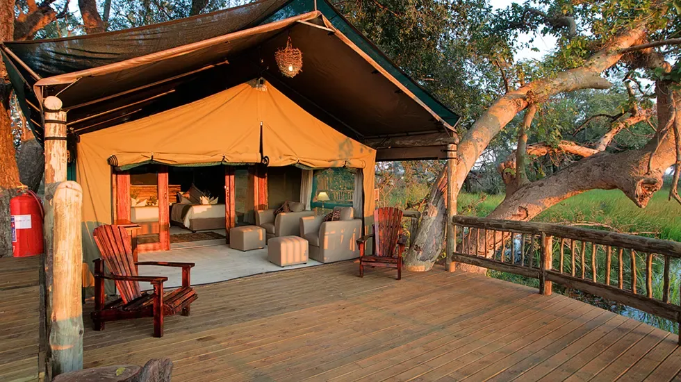 A tented suite at Gunns Camp, Botswana, opening onto a wooden deck among the trees.