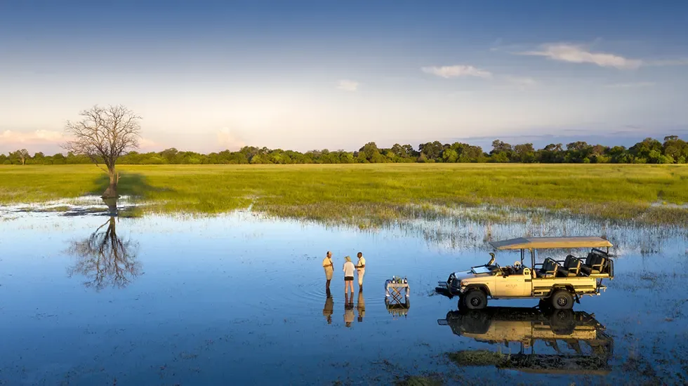 Guests and their guide pause in the shallow floodwaters of the Khwai Concession, Botswana.
