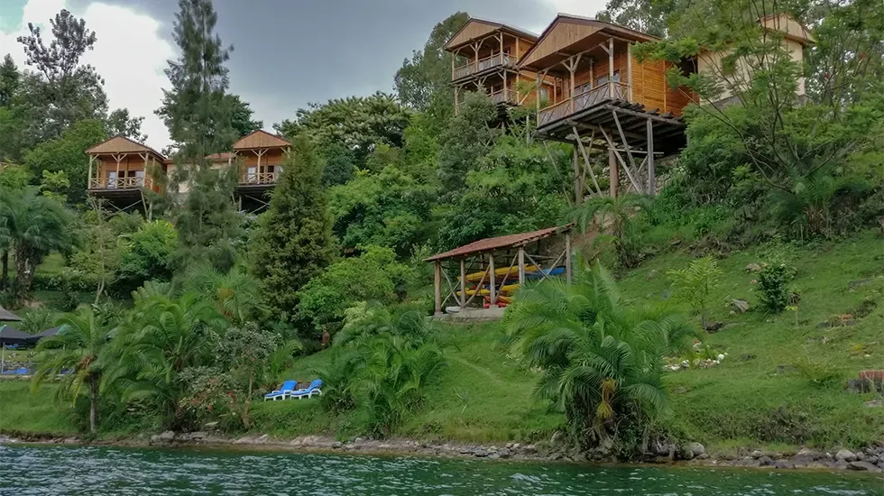 Timber lodges on a green hillside above the water at Kibuye, Rwanda.