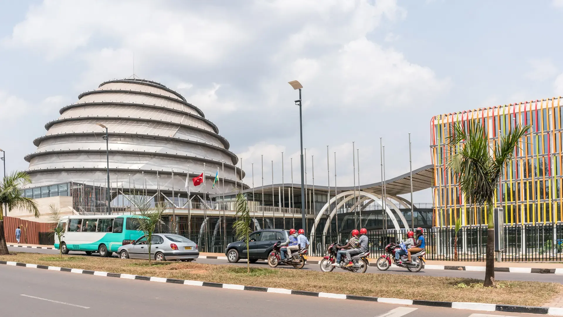 Roadside view in Kigali, Rwanda, with the domed convention centre and passing traffic.