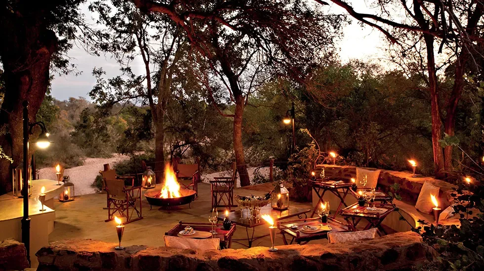 Evening falls over the fire pit and dining terrace at Kings Camp, South Africa.