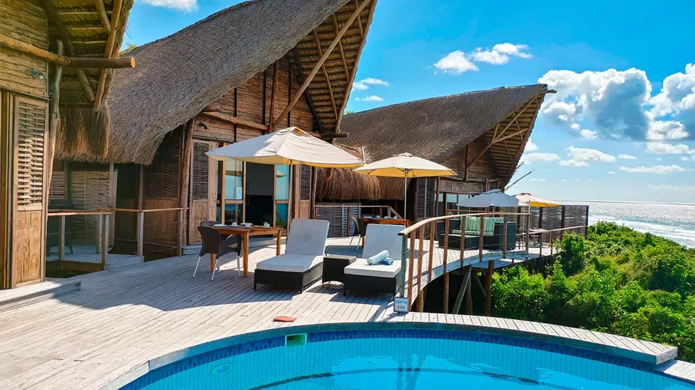 Sun loungers and pool on a wooden deck overlooking the ocean at Massinga Beach.