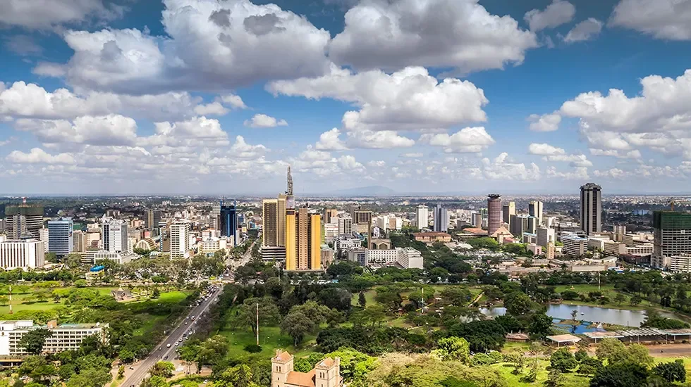 Nairobi's high-rise skyline rising beyond green parkland and open road.