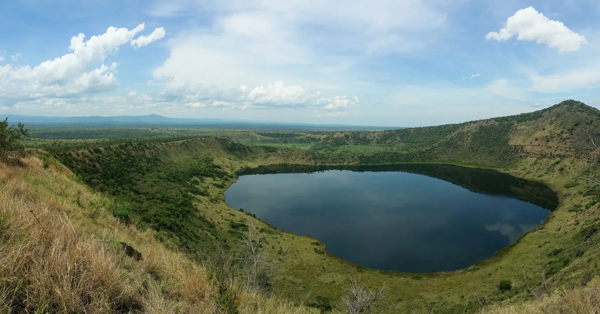A crater lake resting among the green hills of Queen Elizabeth National Park, Uganda.