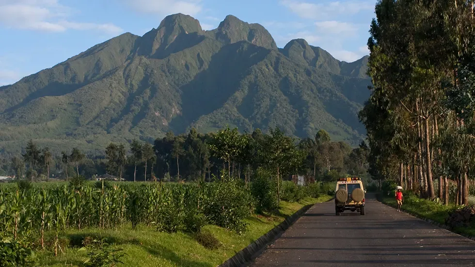 A safari vehicle on the road beneath the Virunga volcanoes near Ruhengeri, Rwanda.