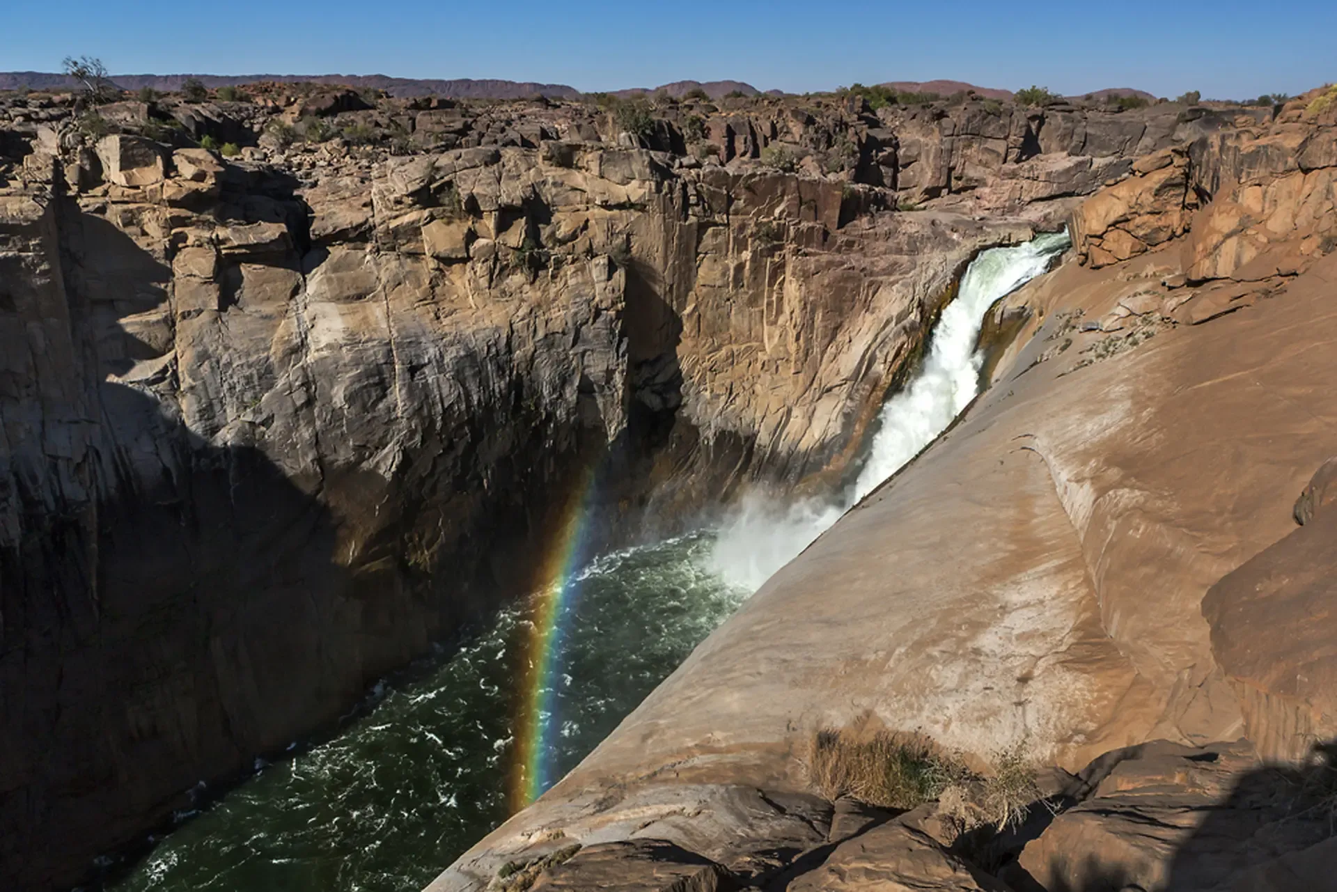 A rainbow forms in the spray of a waterfall in South Africa.