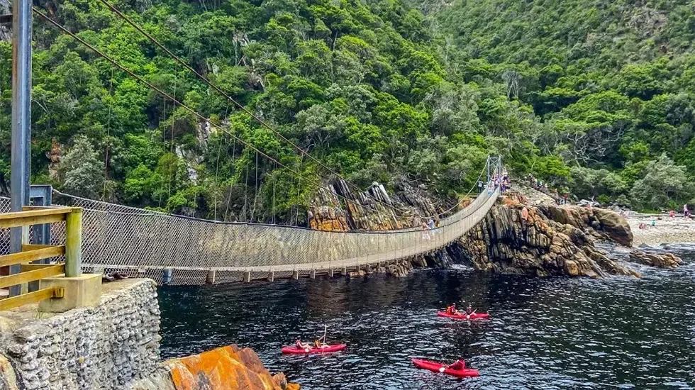 Kayakers paddle beneath the suspension bridge at Storms River in Tsitsikamma National Park.