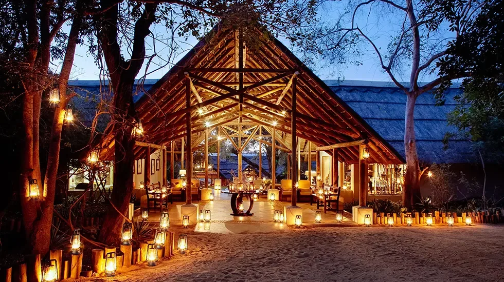 Lanterns light the sandy path to the open-air lodge at Thornybush, South Africa, at dusk.