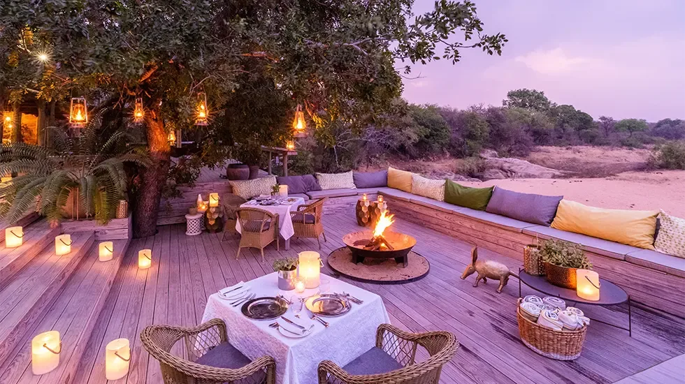 Candlelit dinner setting on the deck at Tangala Safari Camp in Thornybush, South Africa.