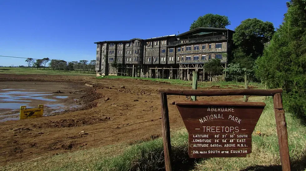 Treetops Hotel in Aberdare National Park, seen across the waterhole from the park sign.
