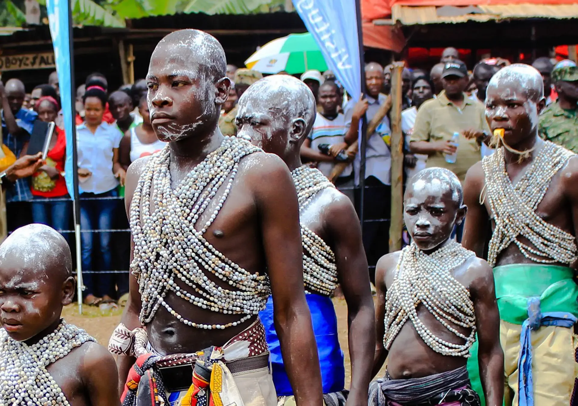Ugandan cultural performers in beaded regalia at a community gathering.