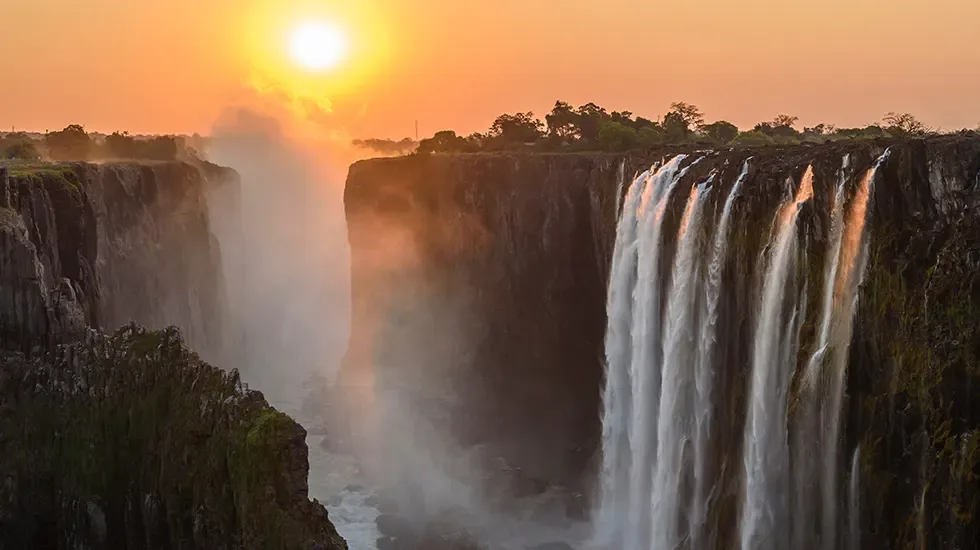 Sunset over Victoria Falls, with mist rising from the gorge below.