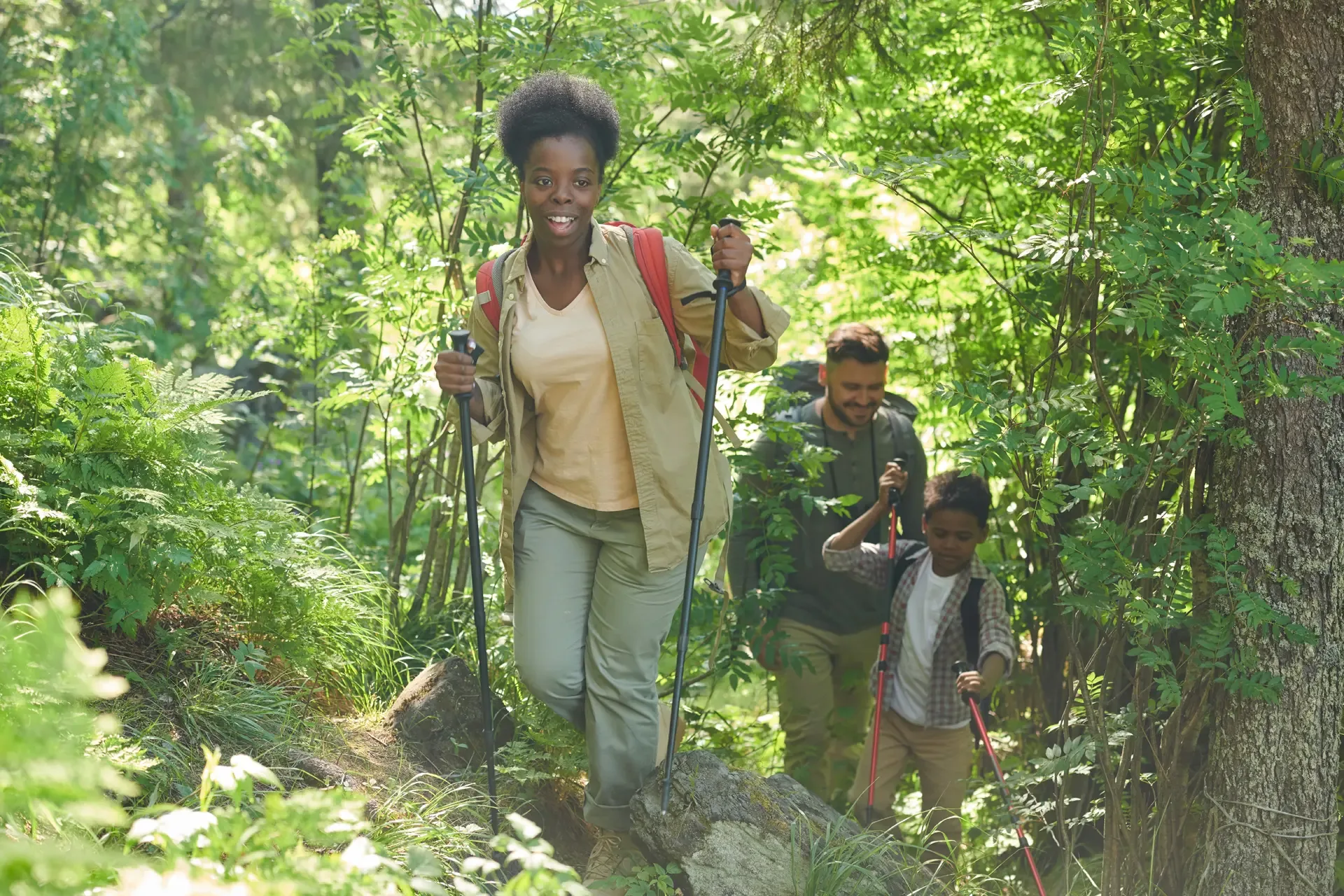 African young woman with backpack walking with sticks she go hiking forest together with her family