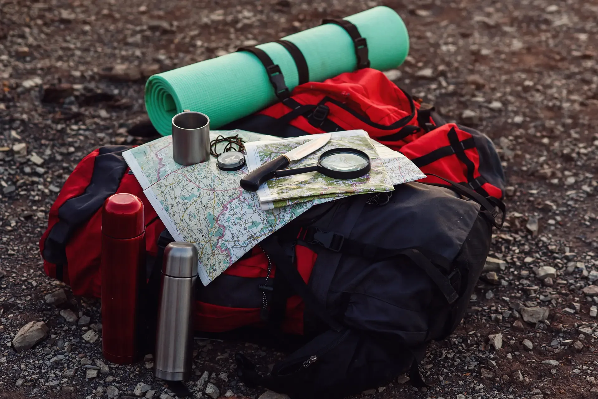 Close up shot travel equipment backpack map compass knife sleeping pad ground