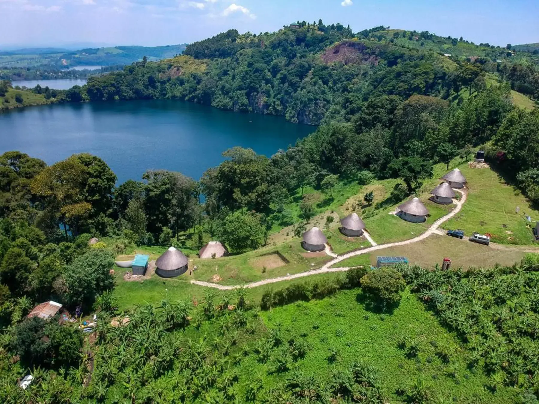 Thatched cottages on a green hillside above a crater lake near Fort Portal, Uganda.