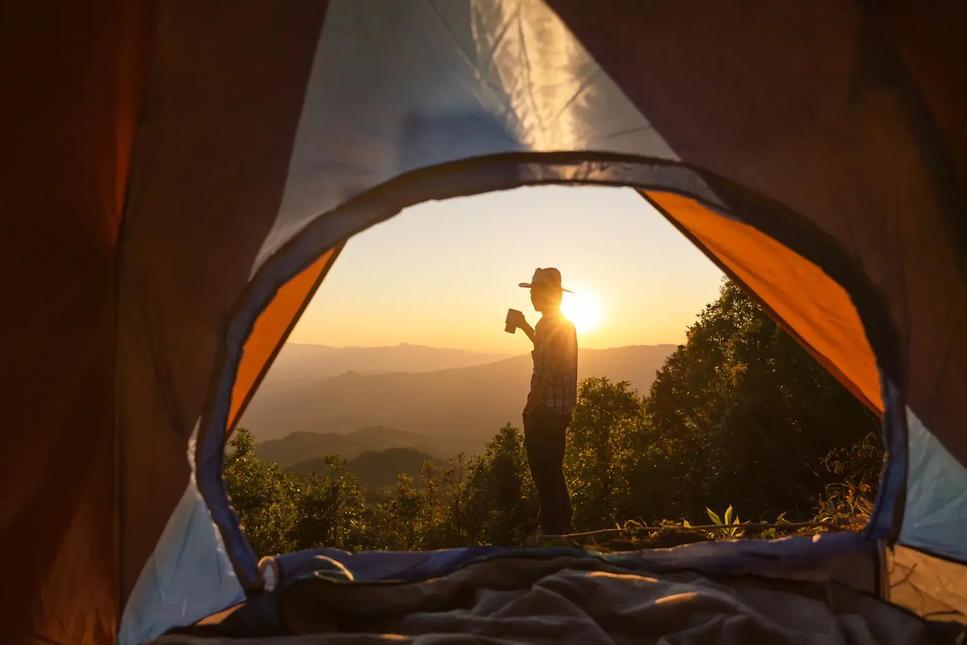 Happy man with holding coffee cup stay near tent around mountains