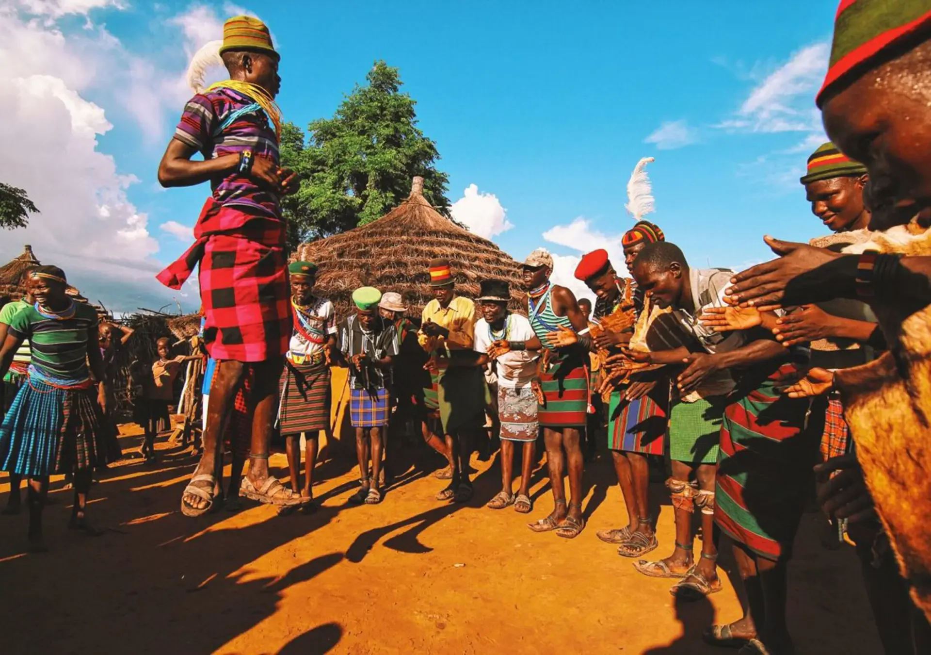 Dancers in colourful dress perform in a Ugandan village, a living window on local culture.