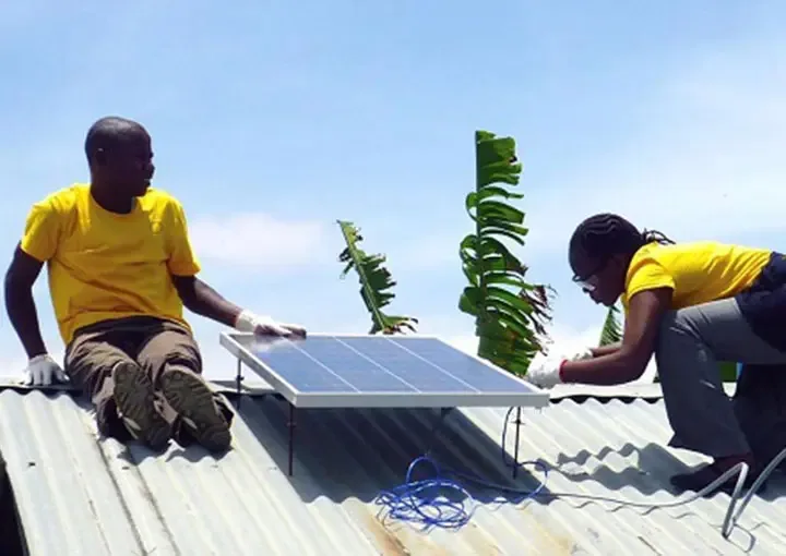 Two technicians fitting a solar panel to a corrugated metal roof