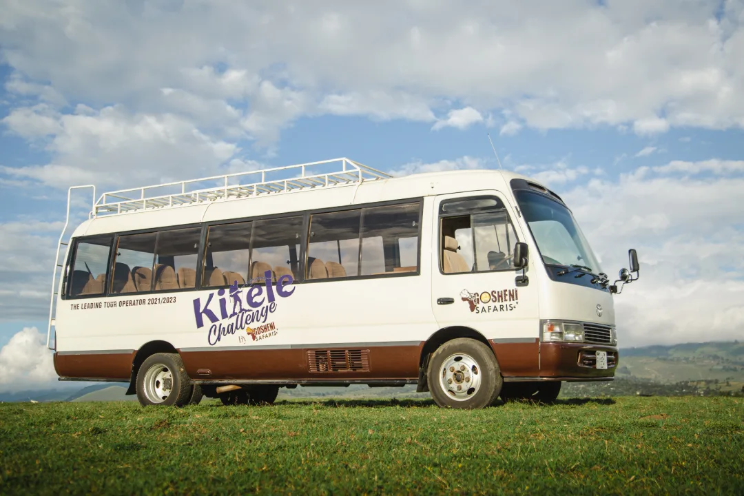 A Gosheni Safaris coach in Kilele Challenge livery parked on a grass ridge